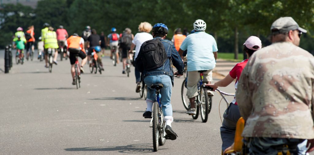 A mass of riders of all ages going through a park on a led ride